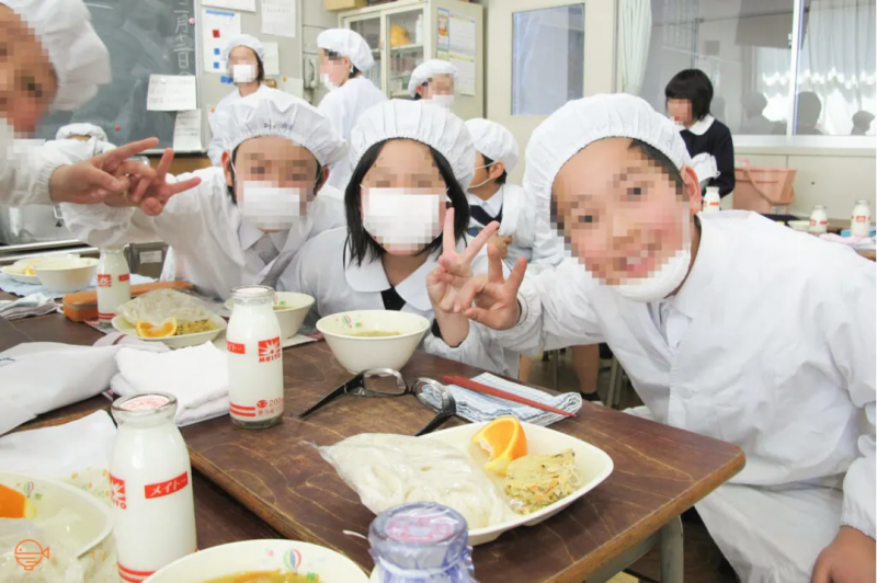 Japanese school students pose with their school lunches.